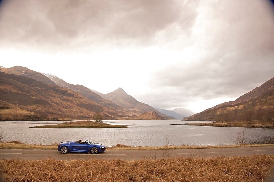 Car on the road by a mountain lake